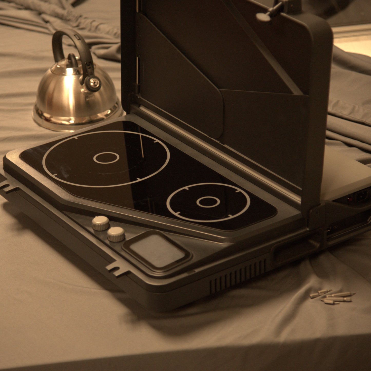 The first portable induction stove and generator with a removable battery and dual burners for campers, outdoor workers, victims of natural disasters — and anyone, anywhere, cooking or surviving off-grid. Pictured here with the lid open with a kettle and also a coffee maker on with the dual burner system is shown in the portable Overlander model. Wind guards are currently pictured also.