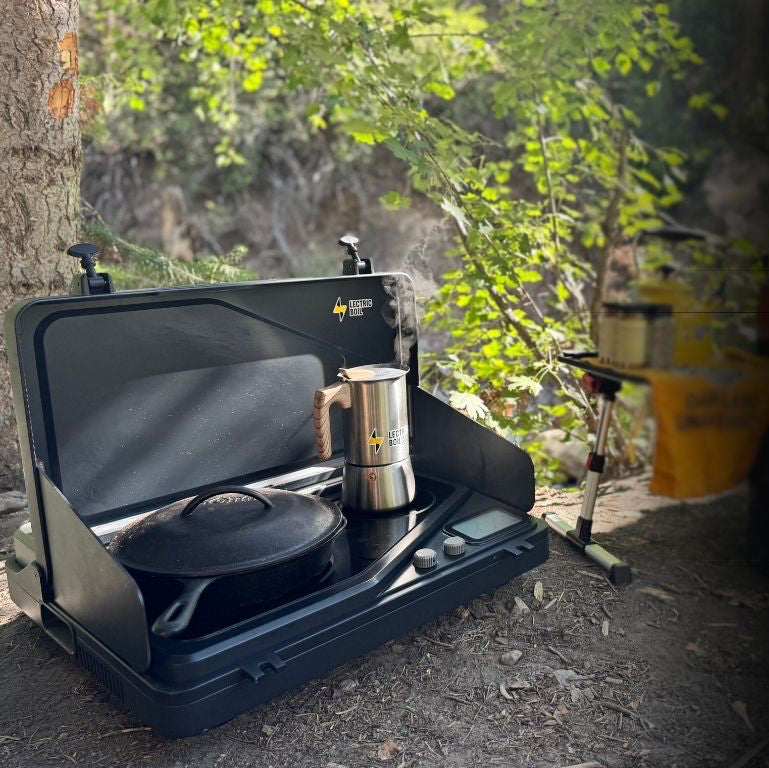 Lectric Boil camping stove with boiling water and a cast iron pan outdoors. The first portable induction stove and generator with a battery and dual burners for campers, outdoor workers, natural disasters — and anyone, anywhere, cooking or surviving off-grid. 